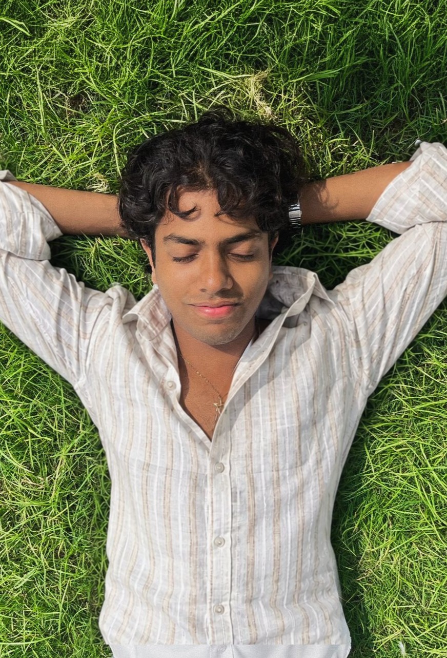 Mauji 100% linen shirt in ivory and sand stripes, worn relaxed while lying on the grass