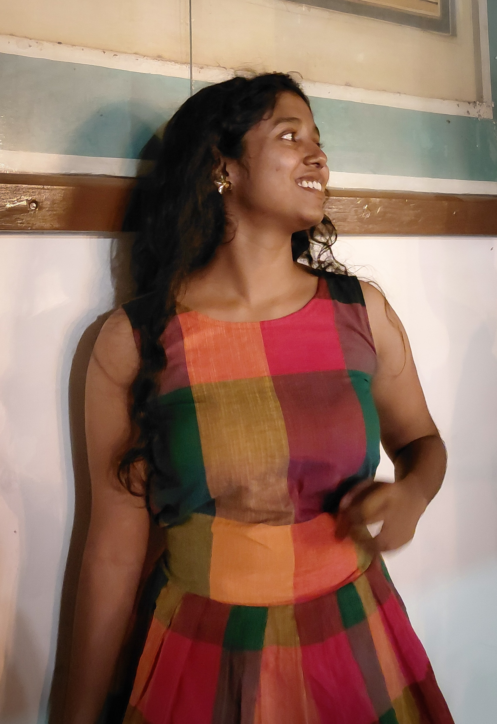 Front view of the Harshavi Madras Muse Dress featuring vibrant multicoloured Madras checks, a sleeveless design, a round neckline, a fitted bodice, and a flared pleated skirt.