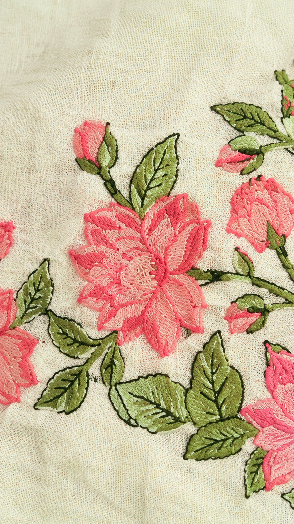 Close-up of Gul’s ivory fabric featuring intricate coral-pink floral embroidery, olive-green leaves, and fine dark outlines, highlighting the raised stitching and natural fabric texture.